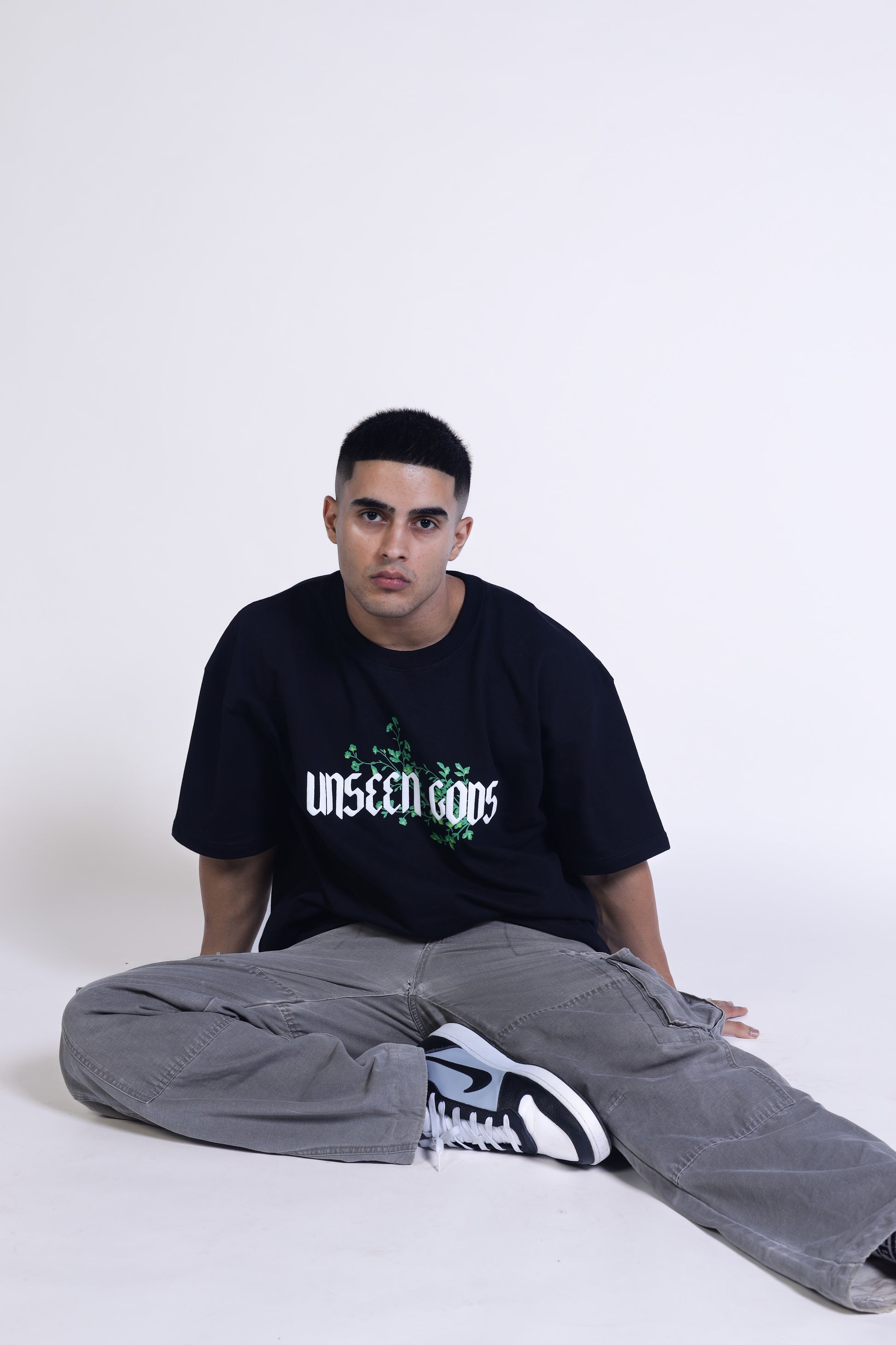 Man sitting wearing black t-shirt of Unseen Gods